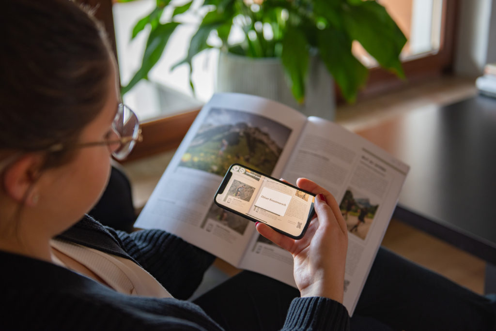 Eine Frau richtet ihr Handy mit einer gestarteten AR-App auf ein Magazin